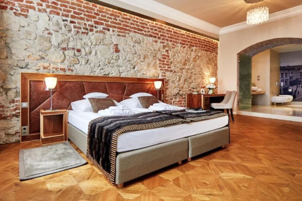 Deluxe room at Alter Hotel in Lublin, featuring exposed historic brick walls, elegant furnishings, and a spacious contemporary design.
