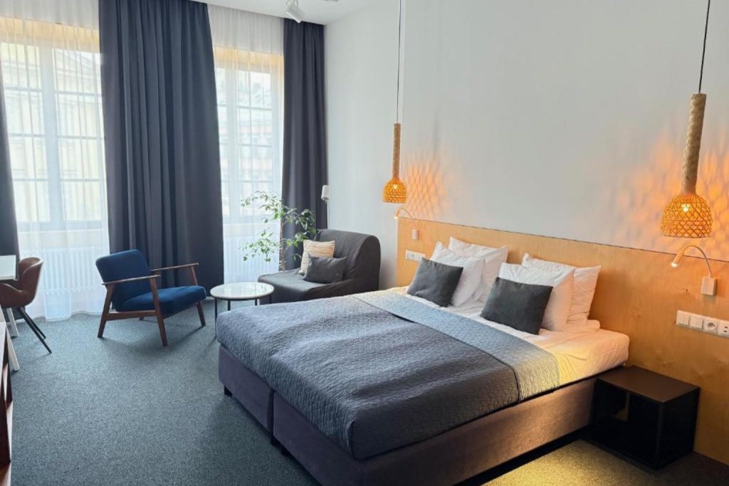 Modern double bedroom with seating area and large windows at Avatary Miasta in Lublin