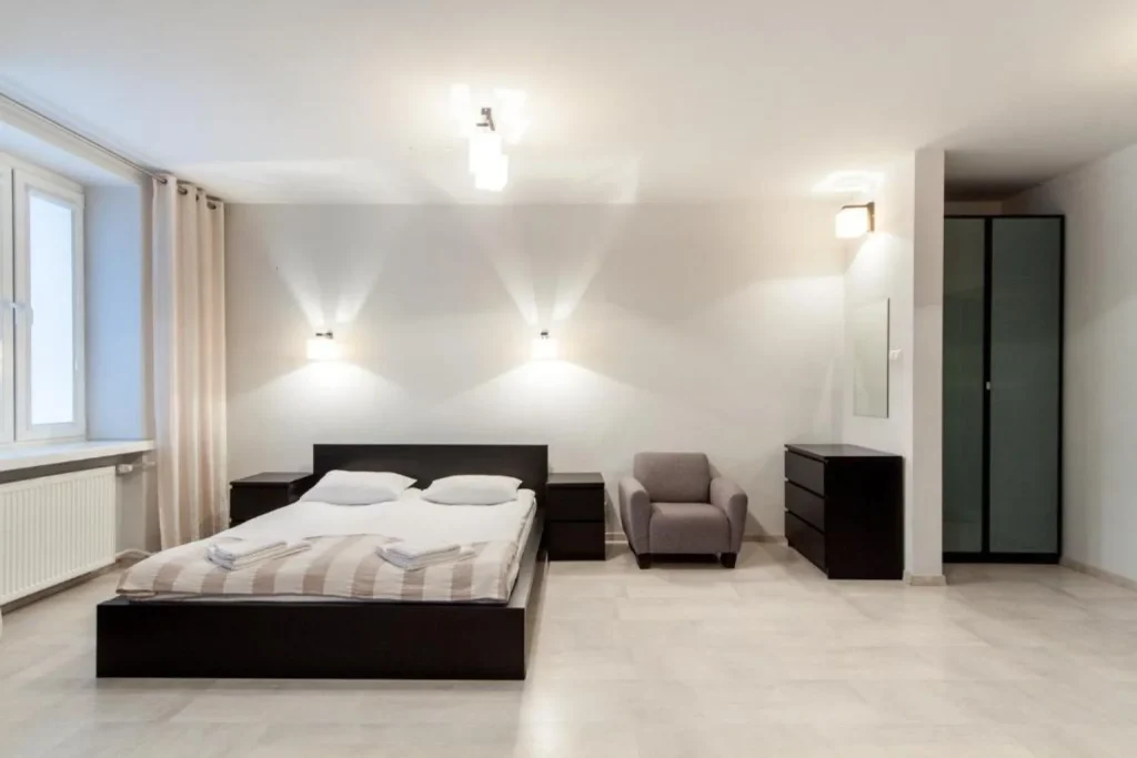 Spacious modern double room with a seating area, wardrobe, and minimalist furnishings at Avion Hotel in Lublin, Poland.