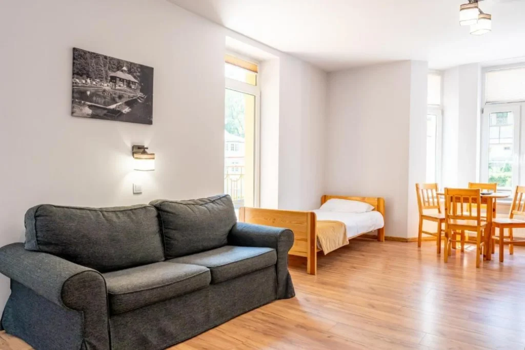 Jasny, przestronny pokój z sofą, łóżkiem oraz częścią jadalną w Hotel Huzar Lublin.