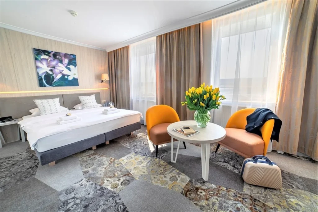 Spacious double room with seating area and large windows at Hotel Victoria in Lublin