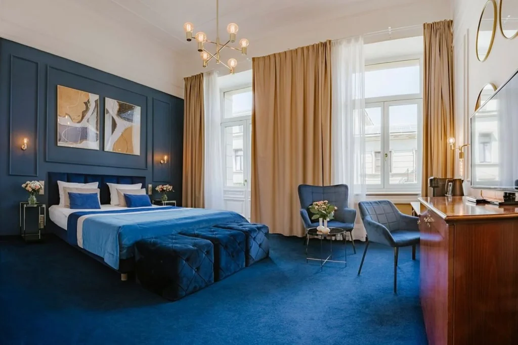 Elegant deluxe guest room with a seating area and high ceilings at IBB Grand Hotel Lublin in Lublin, Poland.