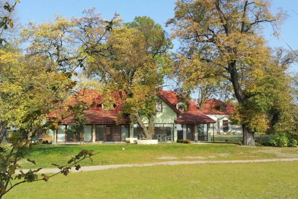 Garden view of the country house surrounded by mature trees and a spacious lawn at Twój Azyl in Lublin, Poland.